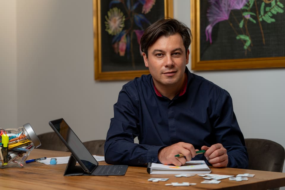 Alexandru Onețiu la masa de lucru, cu o tabletă și un carnet