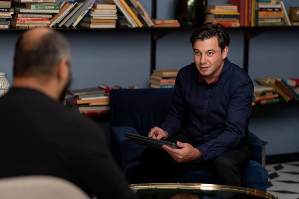 Alexandru Onețiu într-o discuție cu un interlocutor, cu o tabletă în mână
